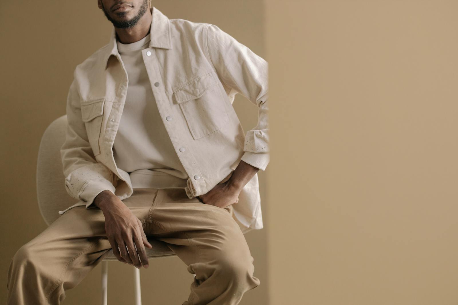 Pièces de garde-robe couleur kaki posées à plat, parka utilitaire et chino en coton, lumière naturelle douce