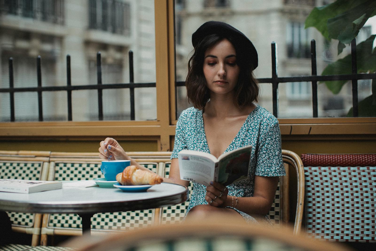 Femme dans un café parisien en marinière et blazer, lumière naturelle douce, ambiance intime éditoriale.