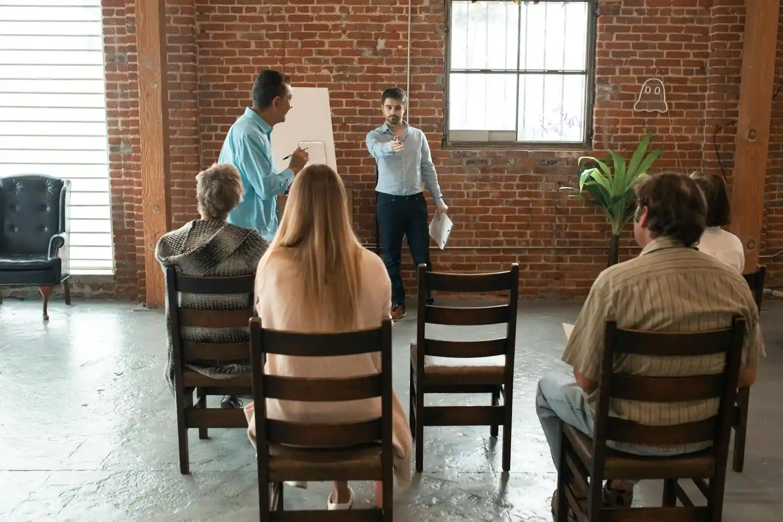 Petit groupe en cercle de discussion lors d'un stage de développement personnel, intervenante debout devant un tableau