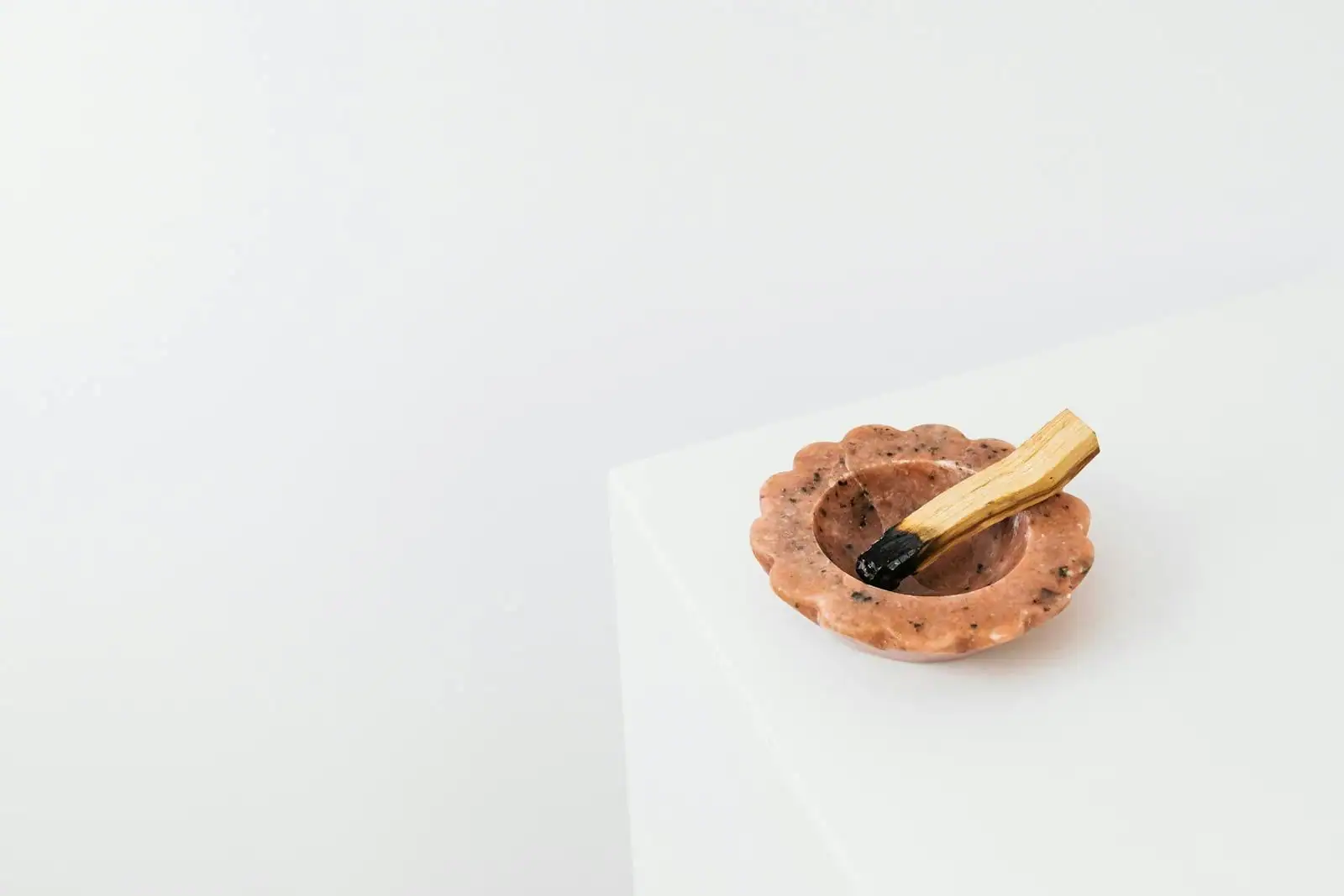 Bâton de palo santo posé sur un plat en céramique avec un peu de fumée s'élevant, ambiance intérieure douce et calme