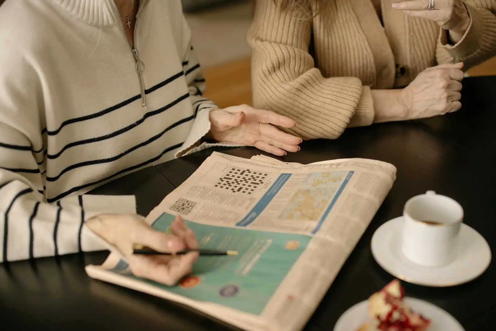Grille de mots croisés posée à côté d'une tasse de café et d'un stylo, scène de rituel matinal