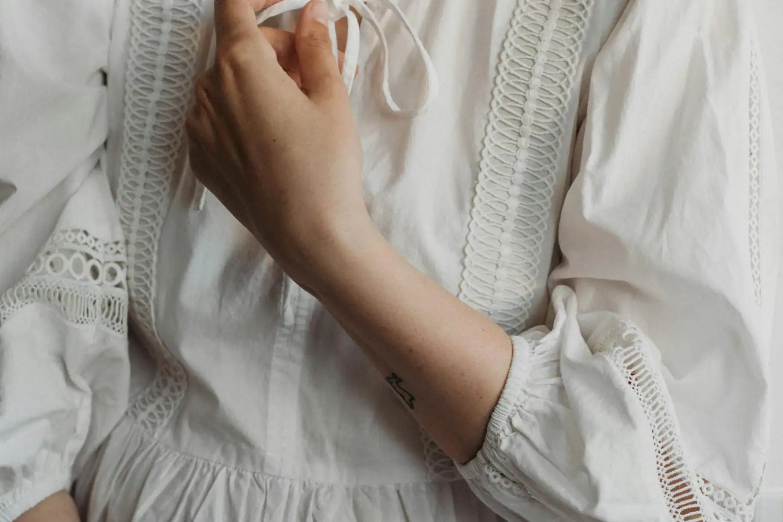 Robe bohème en lin lavé écru avec broderies blanches discrètes, portée en lumière naturelle douce, ambiance éditoriale