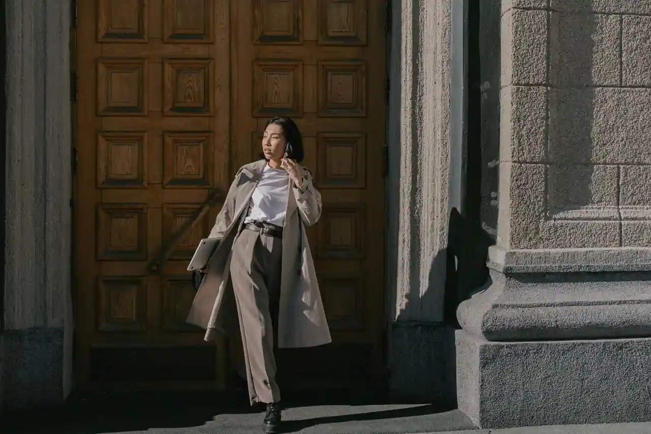 Silhouette mode contemporaine en pantalon ample et manteau long sur une rue urbaine, palette beige et chocolat