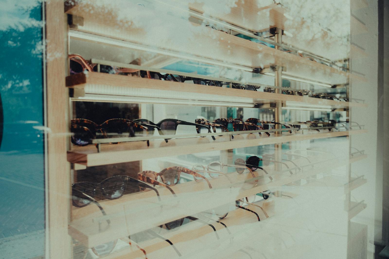 Boutique d'opticien avec montures alignées sur présentoirs lumineux, ambiance commerciale moderne et lisible