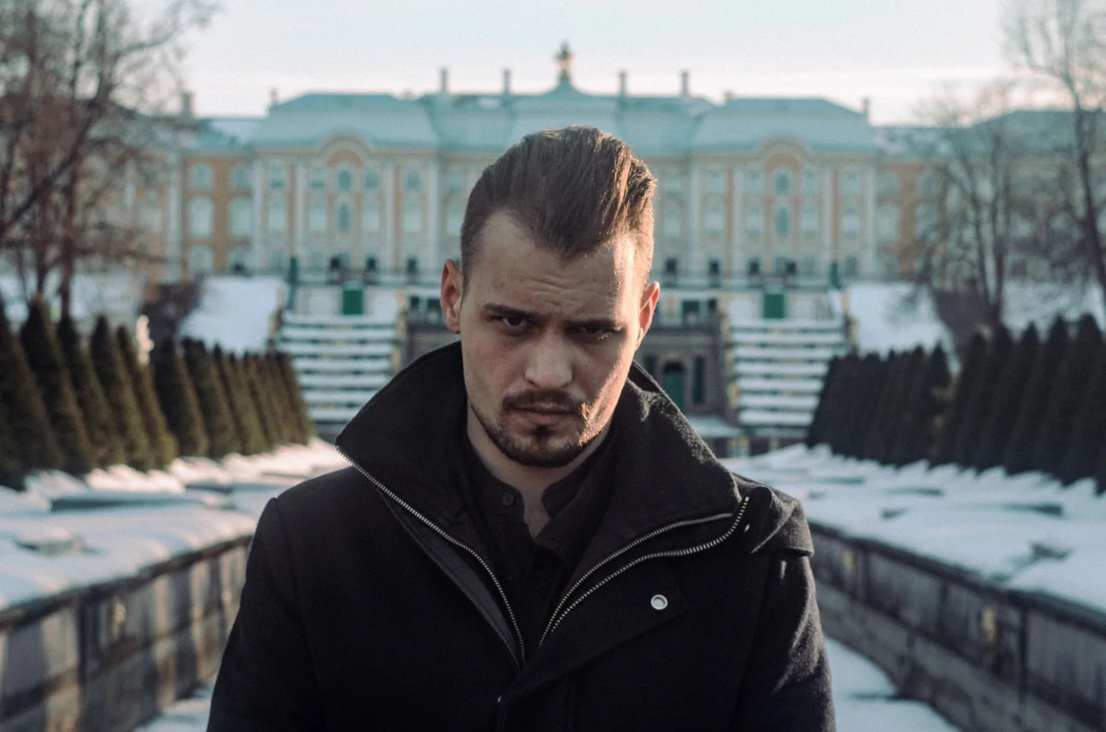 Portrait d'un homme aux cheveux bruns plaqués en arrière, coiffure gominée souple, en extérieur