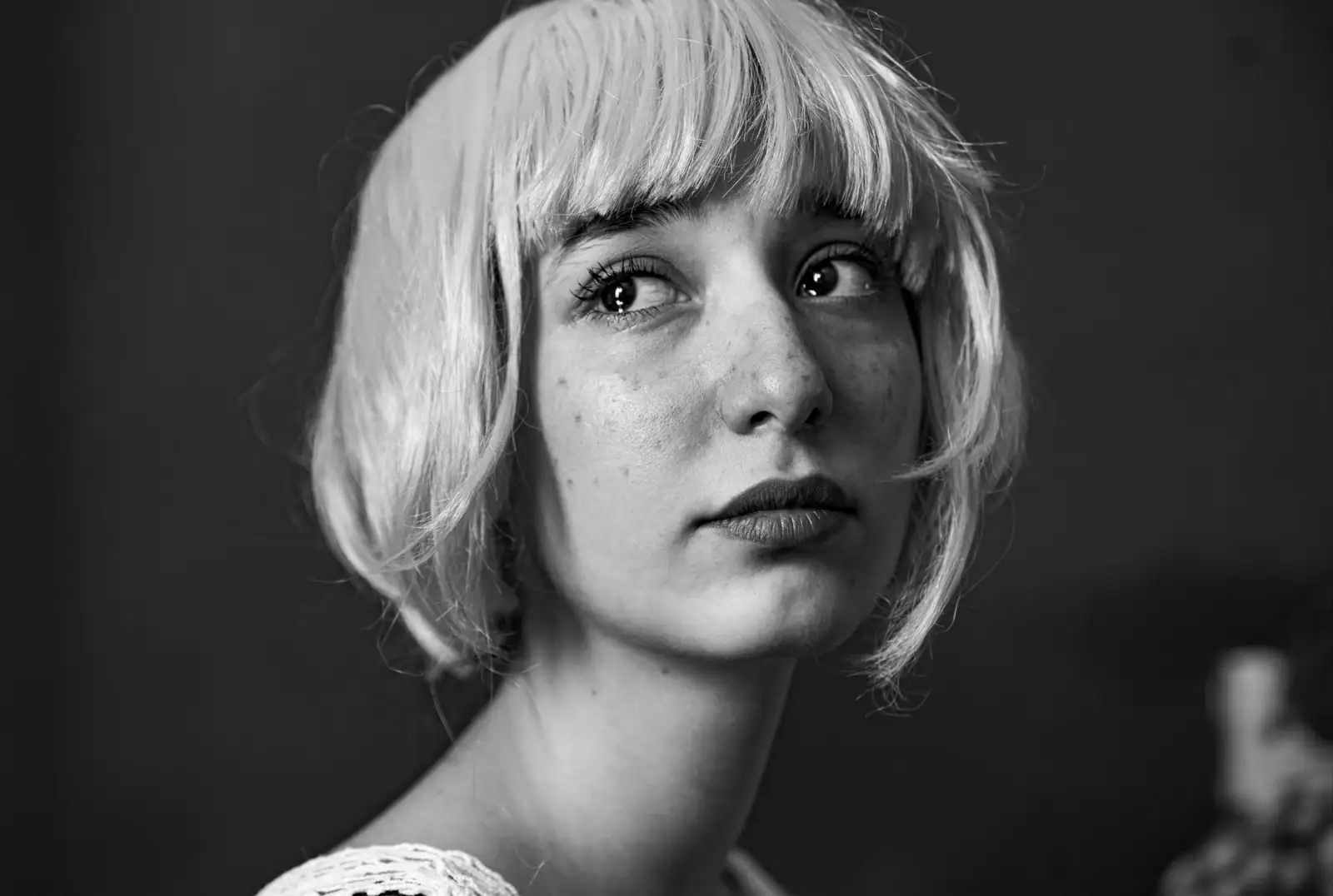 Femme blonde coiffée d'un carré court avec frange, portrait en noir et blanc.