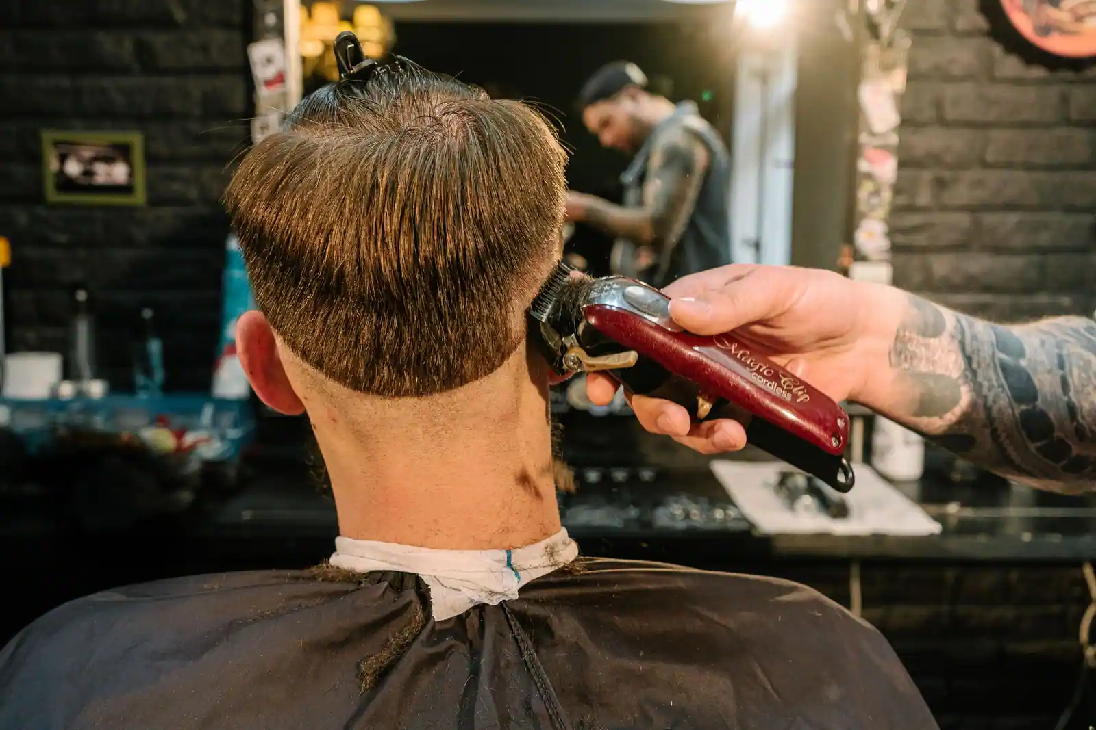Vue de dos d'un homme chez le coiffeur, cheveux dégradés en douceur à la tondeuse sur la nuque et les côtés