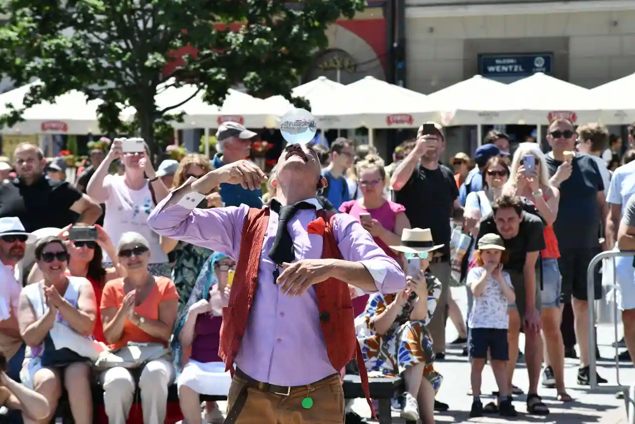 Un artiste de rue joue devant un public rassemblé en plein air lors d'un festival d'arts de la rue.