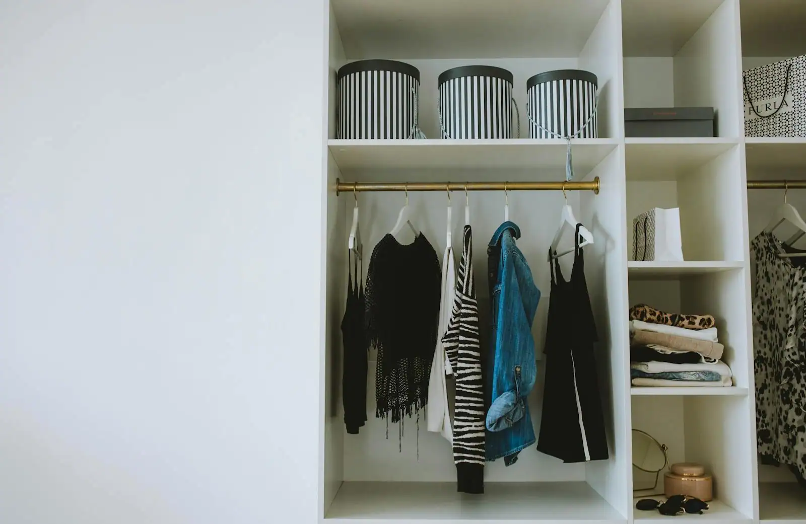 Dressing ouvert et bien rangé, vêtements suspendus à une tringle et boîtes de rangement sur l'étagère