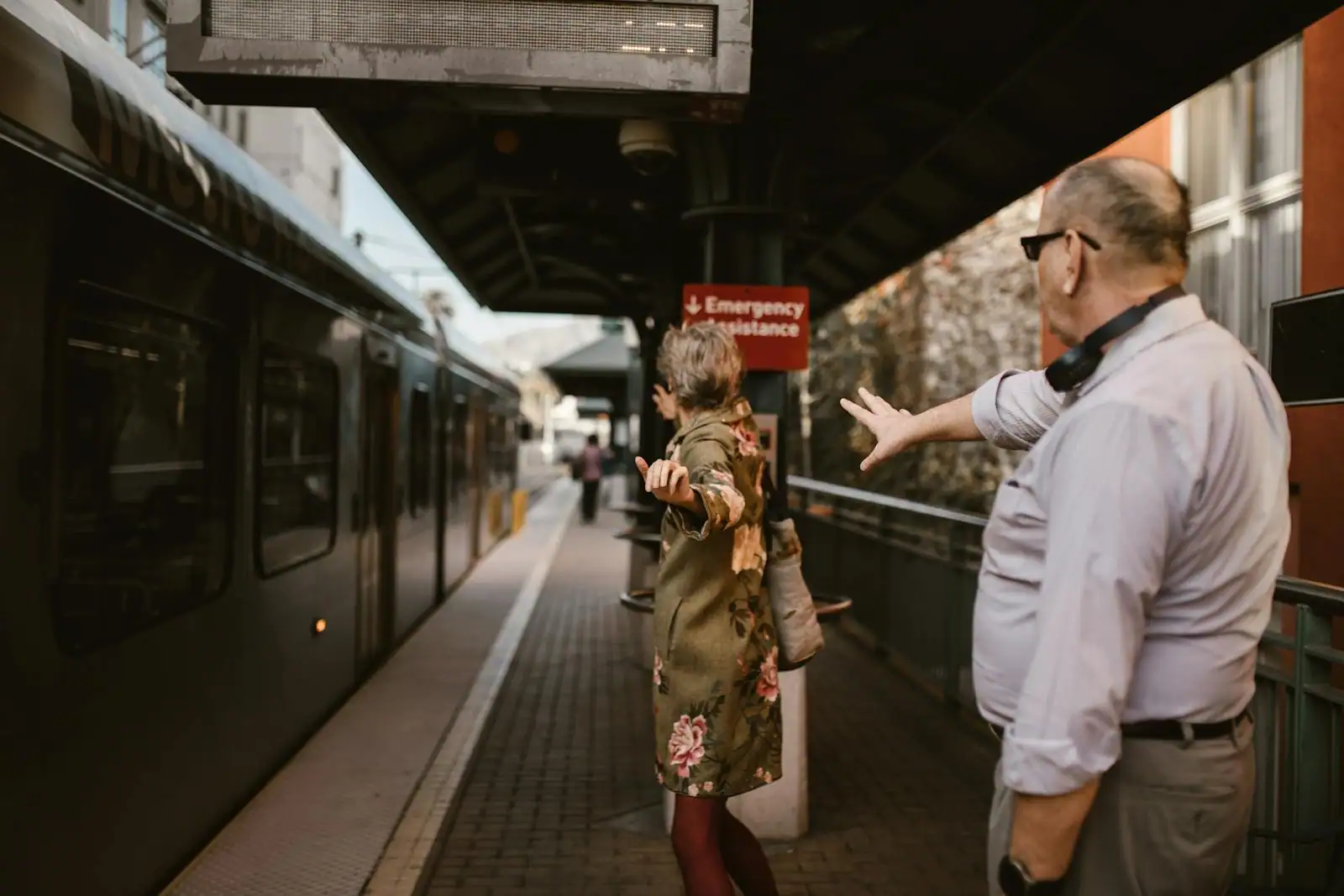 Sur un quai de gare, une femme tend les bras vers un homme, un train à l'arrêt juste à côté