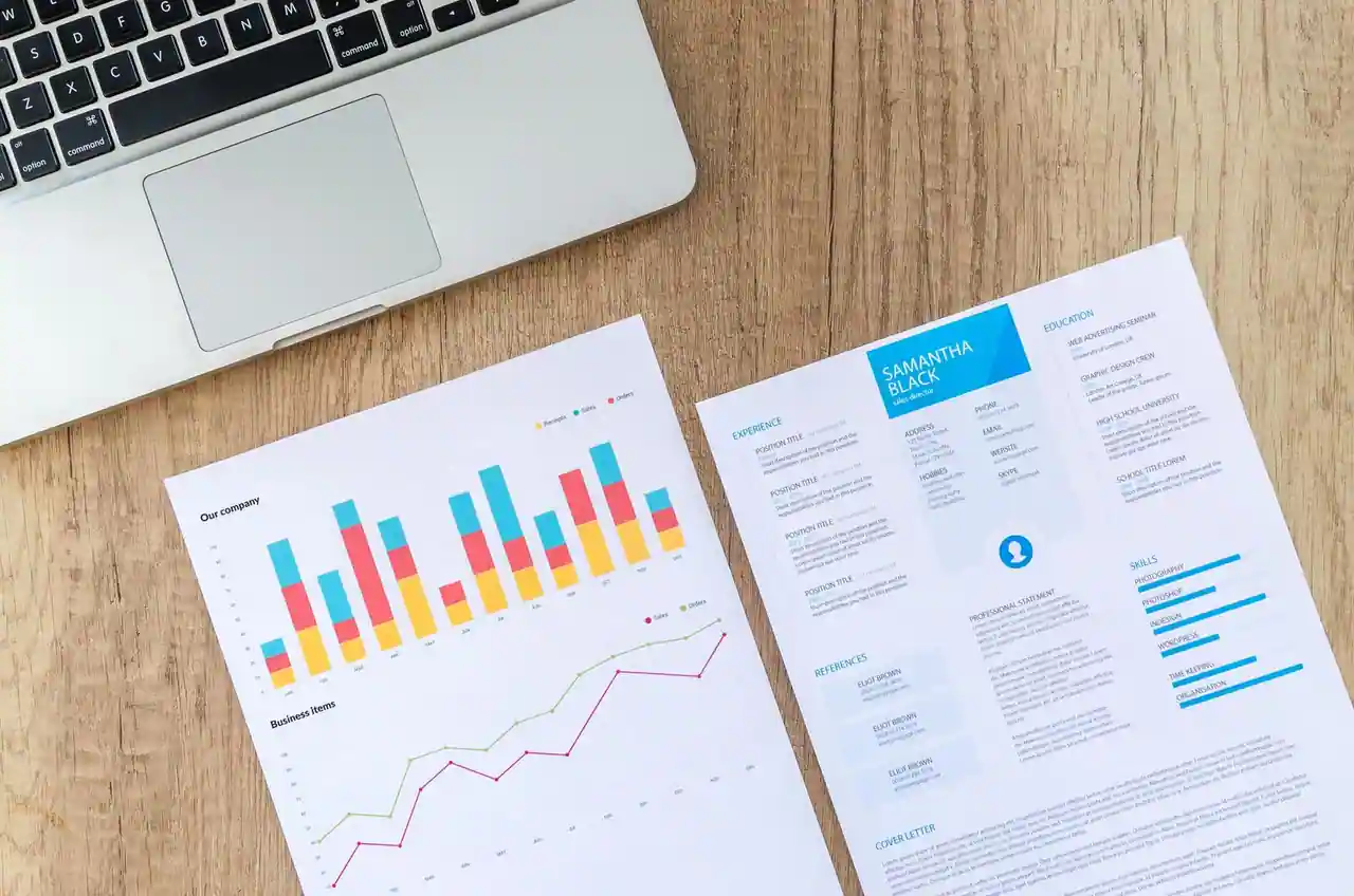 Curriculum vitae imprimé posé sur un bureau à côté d'un ordinateur portable, avec sa rubrique centres d'intérêt visible
