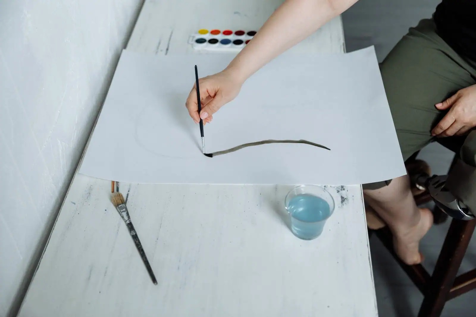 Personne peignant à l'aquarelle sur une table, illustrant une activité de loisir créatif