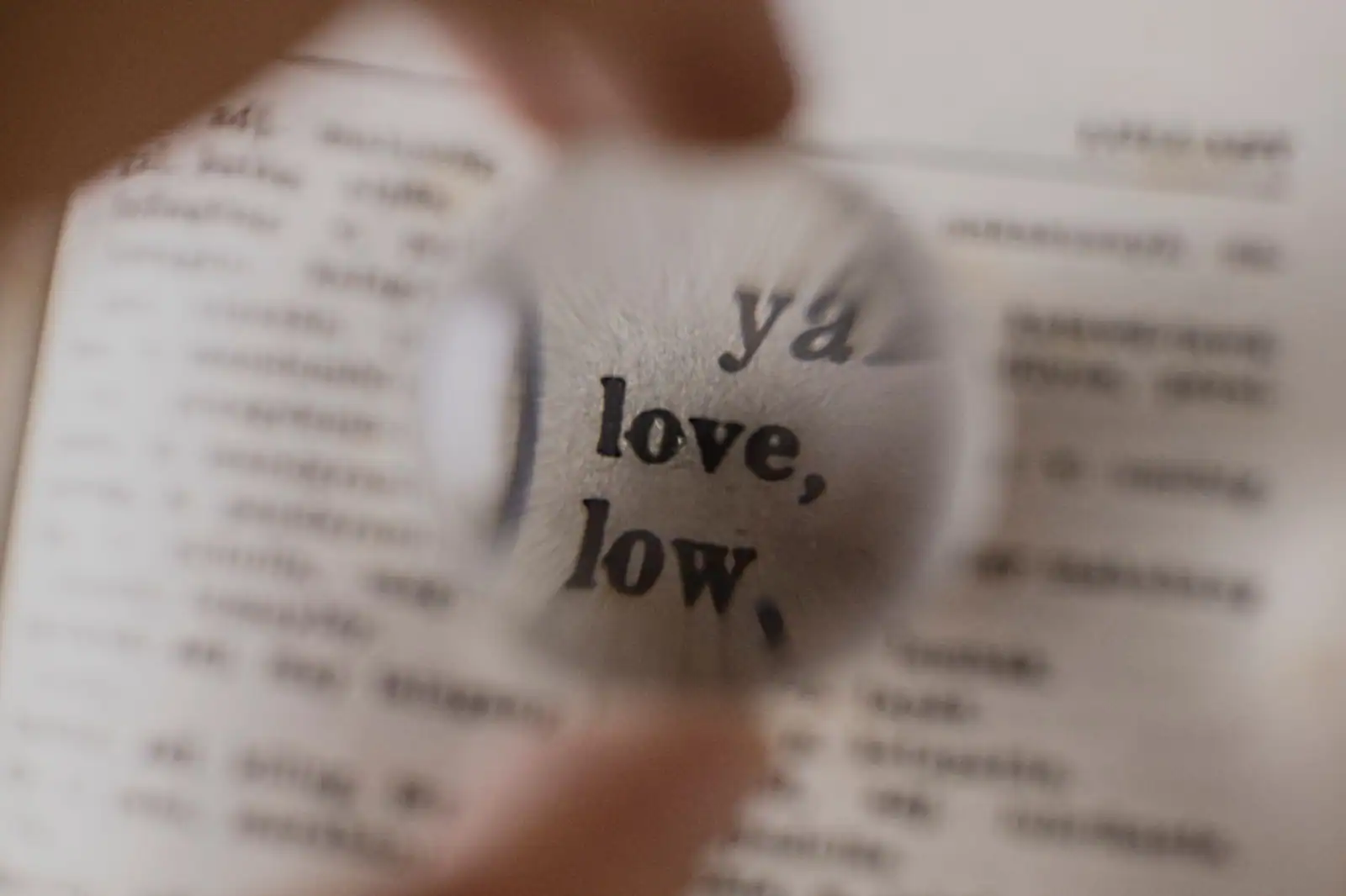 Loupe grossissant un mot sur une page de dictionnaire, évoquant la recherche du terme juste.