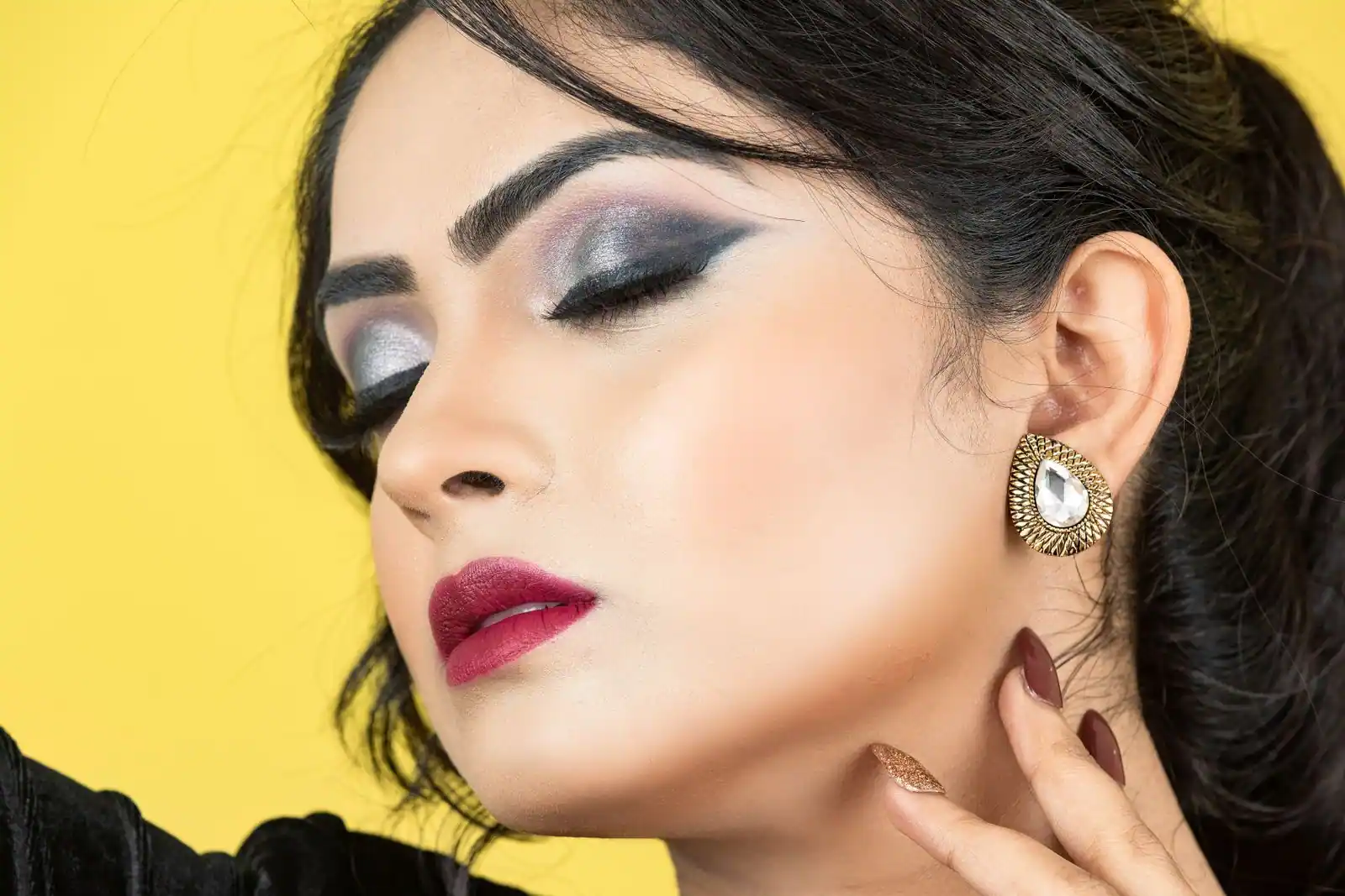 Portrait en gros plan d'une femme au maquillage de soirée appuyé : smoky argenté, sourcils marqués et lèvres prune