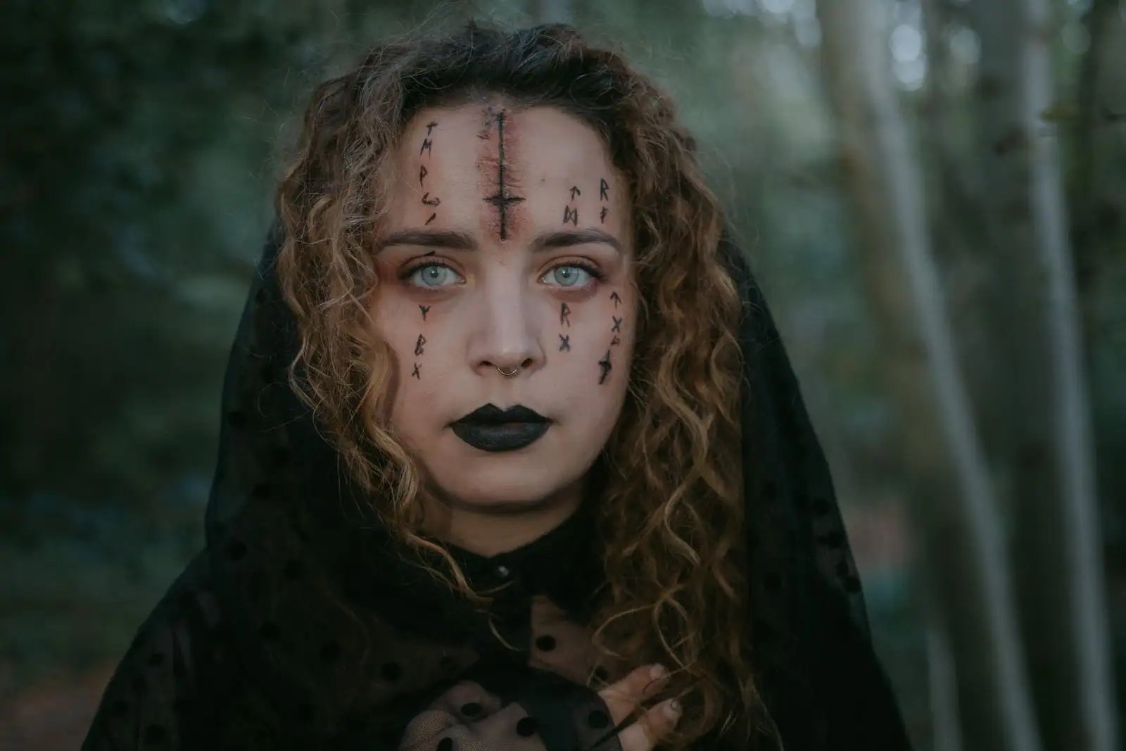 Portrait d'une femme maquillée pour Halloween, symboles noirs tracés au crayon sur le visage et lèvres sombres
