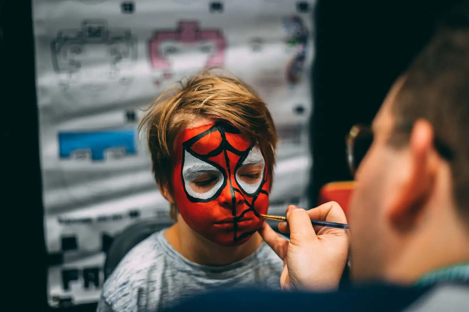 Enfant au visage peint en super-héros rouge et noir, maquillé au pinceau par un adulte
