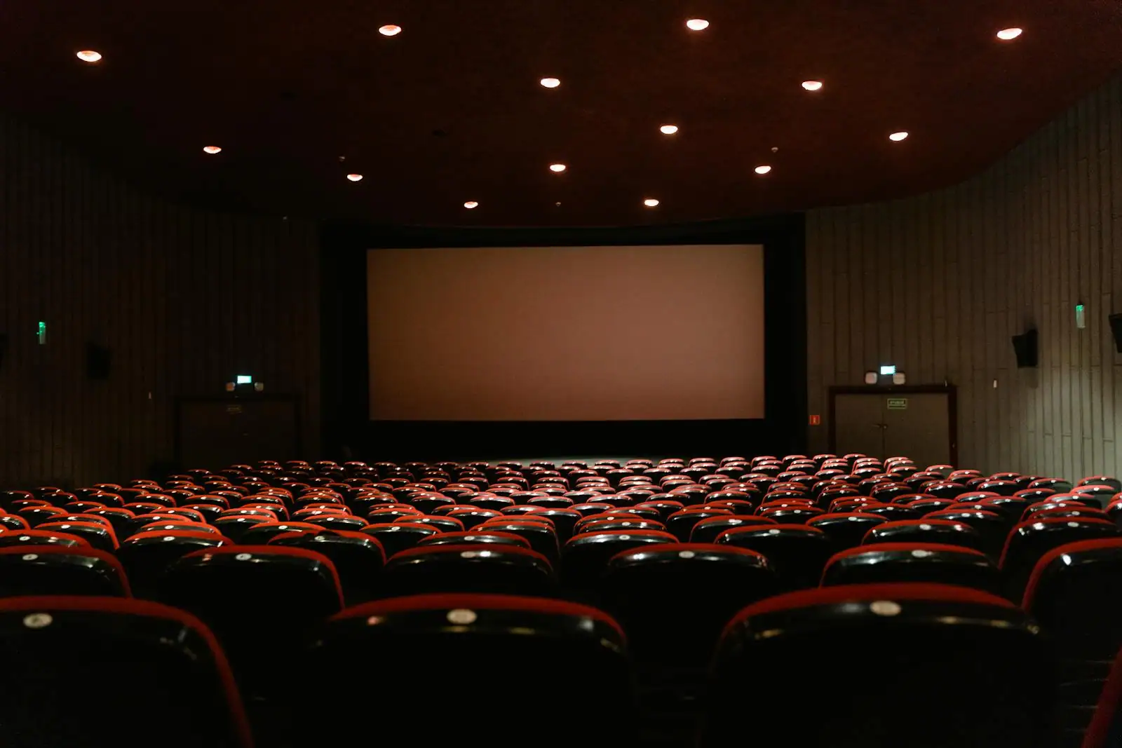 Salle de cinéma plongée dans le noir, écran lumineux et rangées de fauteuils