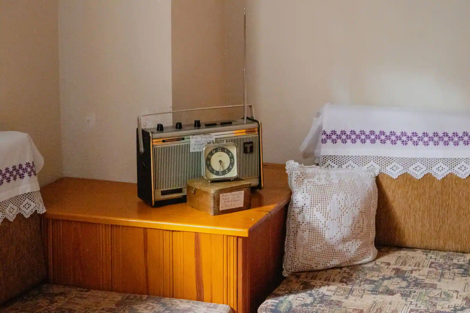 Poste de radio vintage sur un meuble en bois, à côté d'un réveil ancien, dans un intérieur chaleureux
