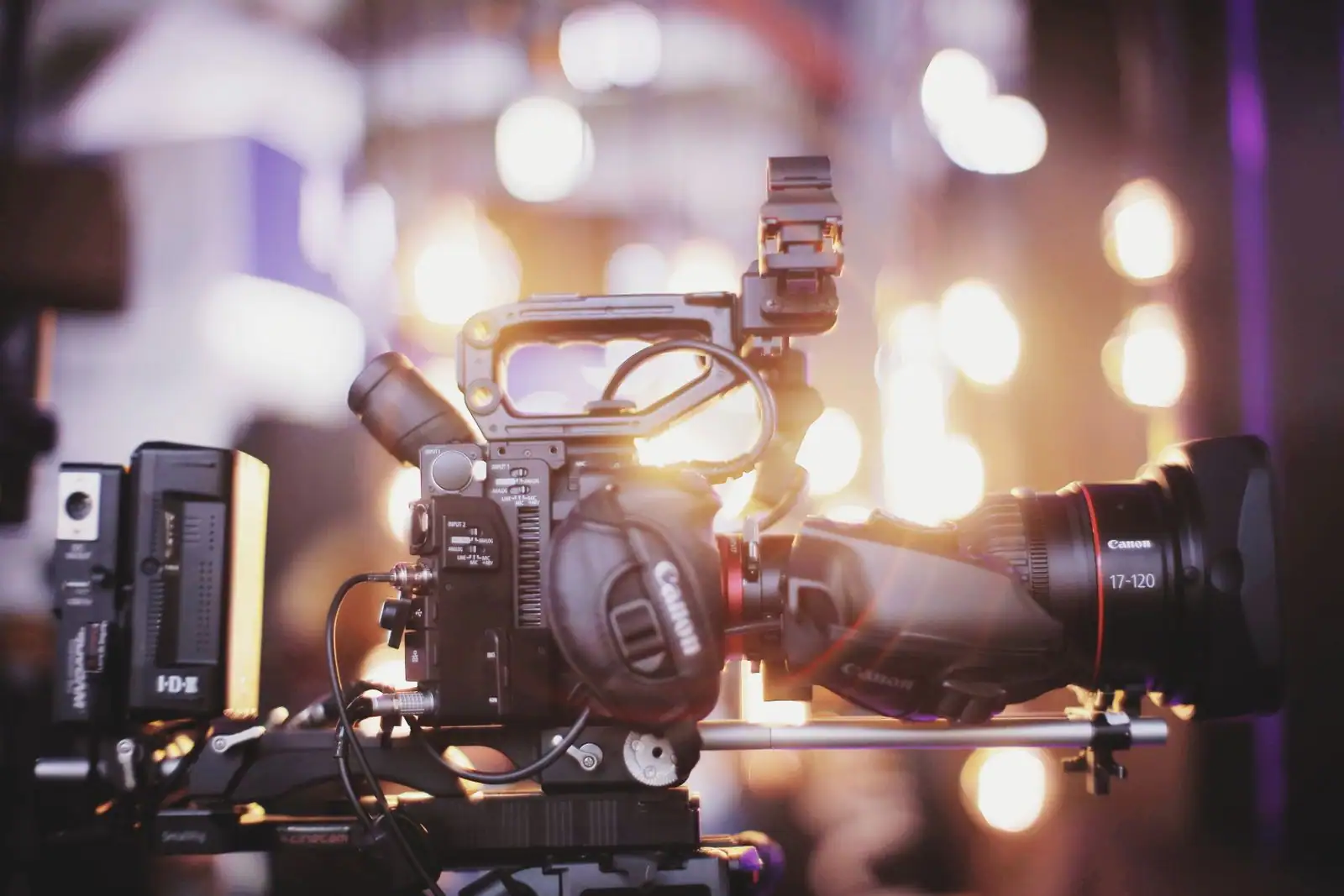 Caméra de cinéma professionnelle avec son objectif, devant des lumières floutées de plateau de tournage