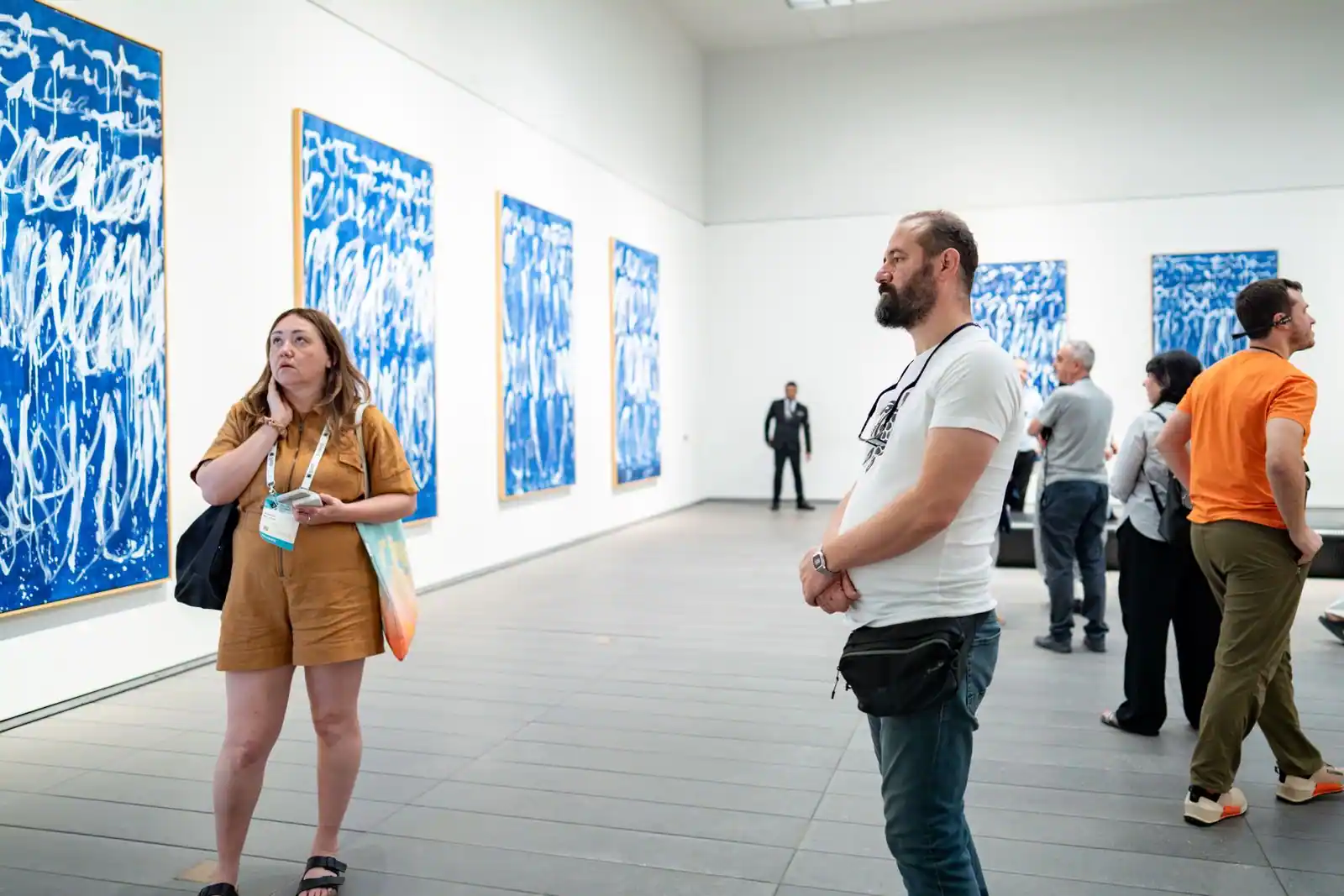 Visiteurs déambulant dans une salle d'exposition d'un musée devant des oeuvres accrochées au mur