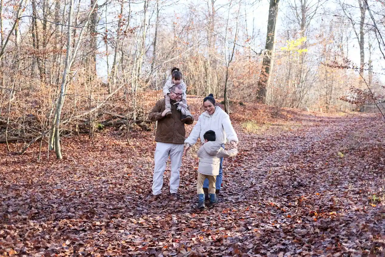 Une famille avec deux enfants marche sur un sentier forestier en automne, illustration d'une sortie du week-end