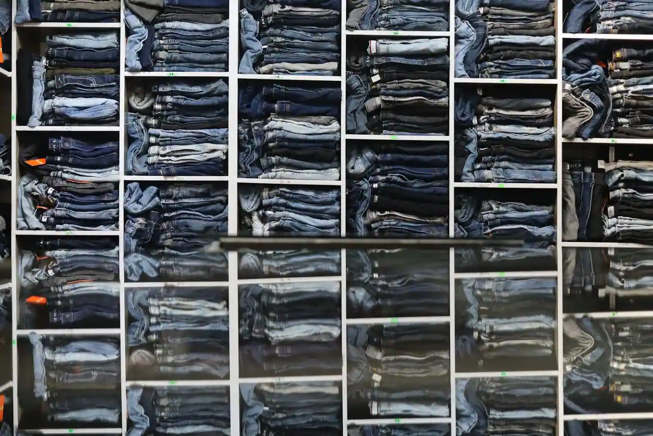 Jeans en denim bleu soigneusement pliés et empilés sur une table en bois dans une boutique de mode