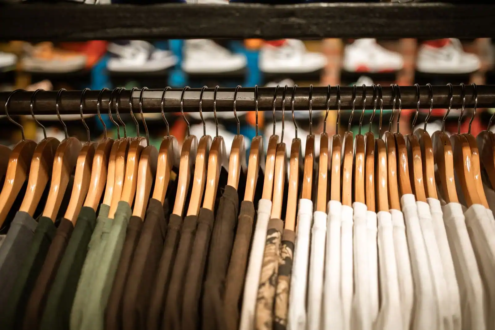 Portant de boutique garni de vêtements serrés sur des cintres en bois, image d'abondance de mode