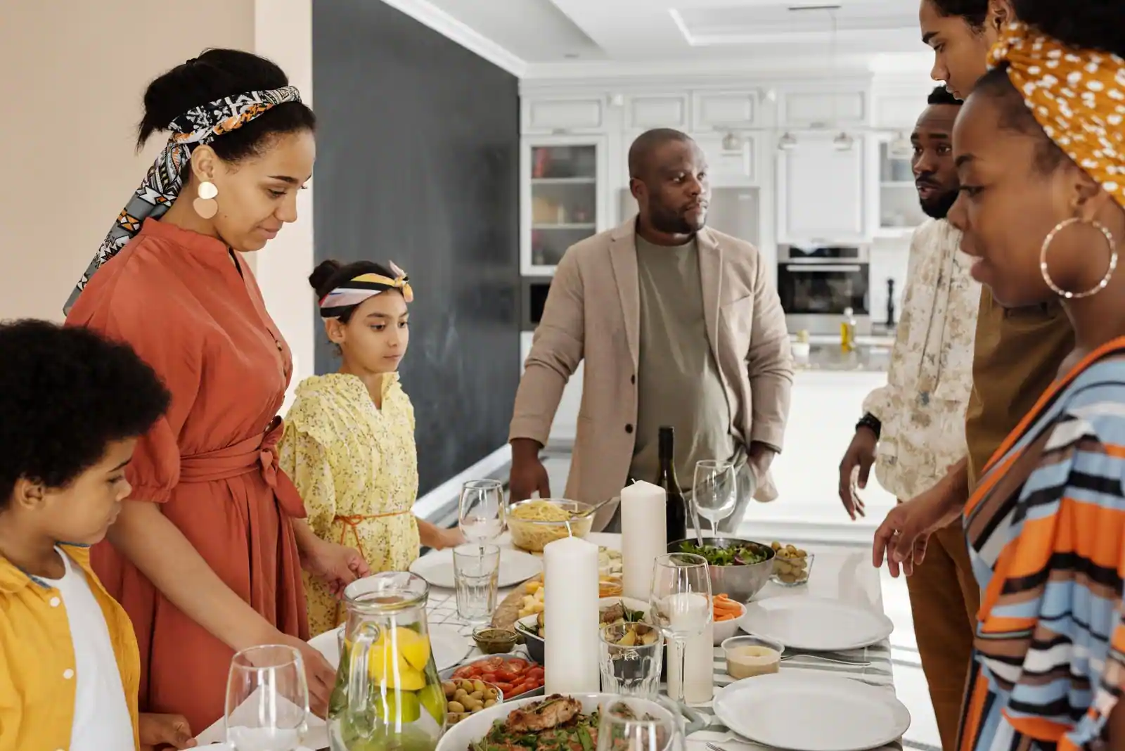 Famille réunie autour d’une table garnie de plats dans une cuisine lumineuse