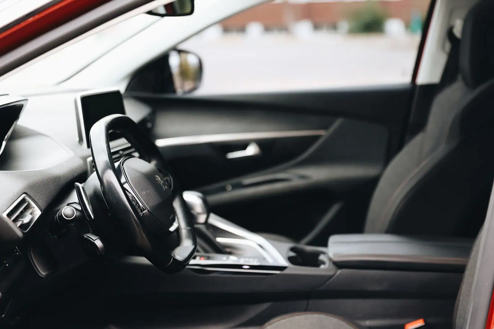 Habitacle avant d'une voiture moderne : volant, écran tactile et console centrale, vue côté passager.