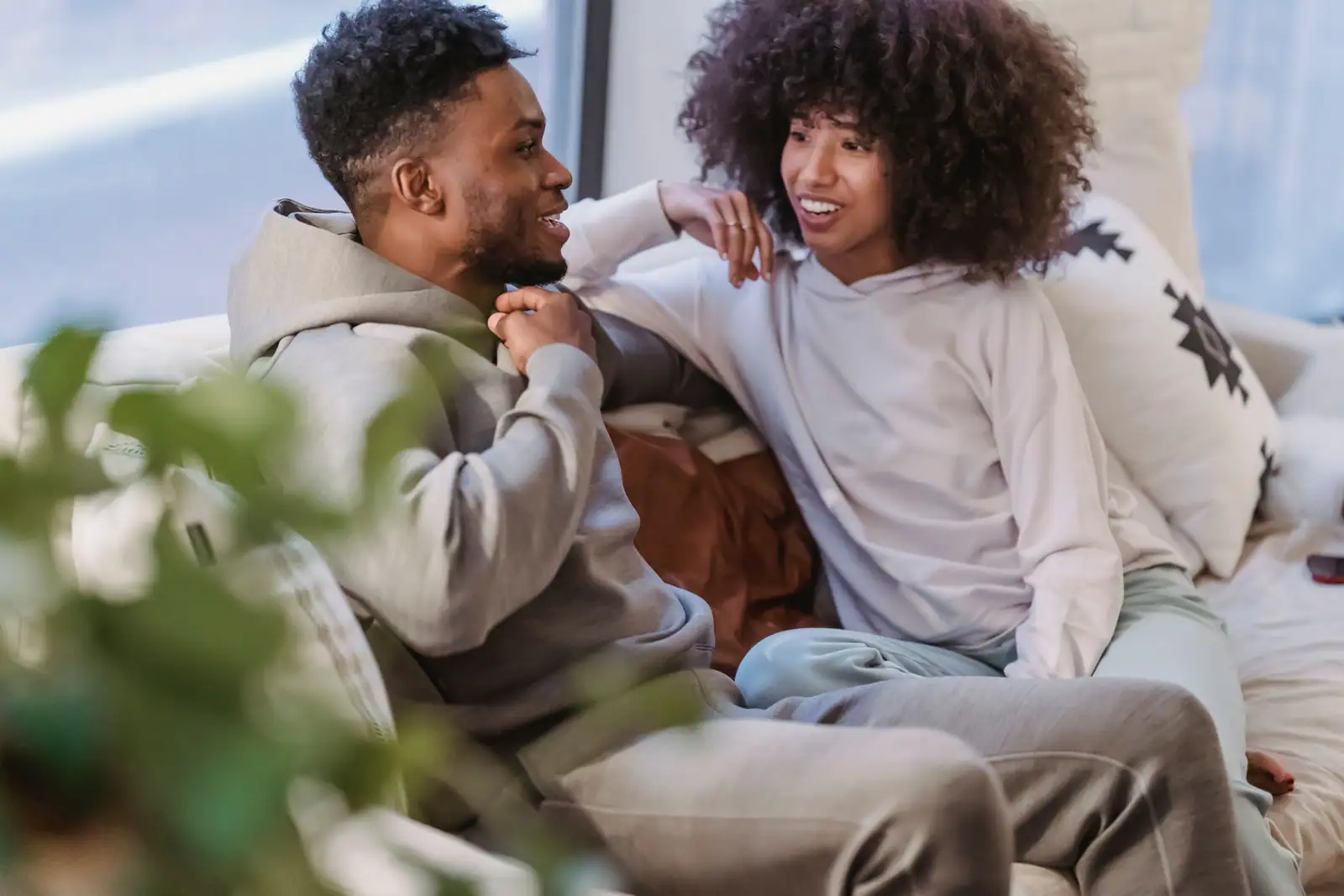 Un couple en tenue d'intérieur, assis sur un canapé, en pleine conversation un jour ordinaire
