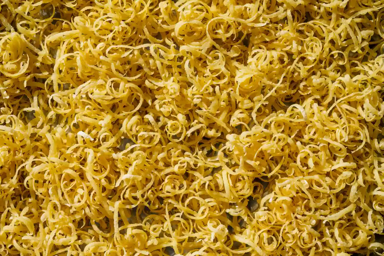 Gros plan sur une masse de fins filaments végétaux dorés, la texture même des cheveux d’ange en cuisine