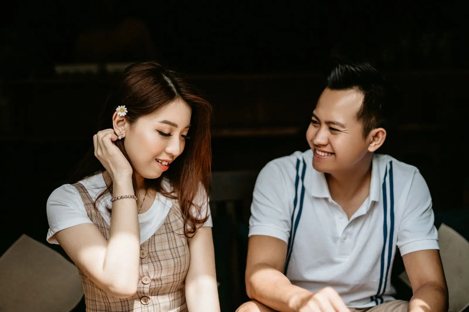 Jeune homme et jeune femme souriants, moment complice dans une lumière chaude.