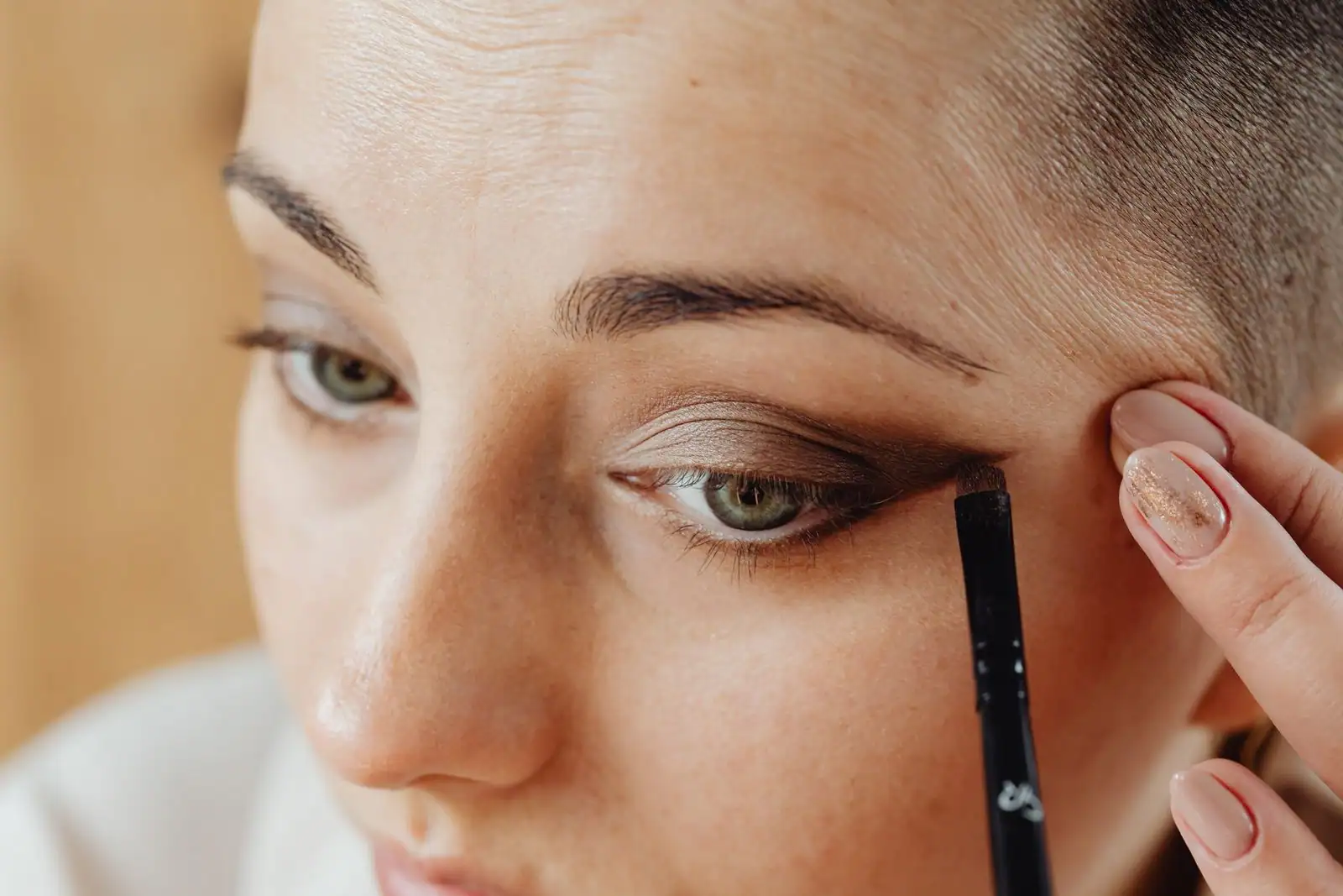 Gros plan sur l'application d'un eye-liner noir graphique au pinceau au coin d'un œil, geste de maquillage.