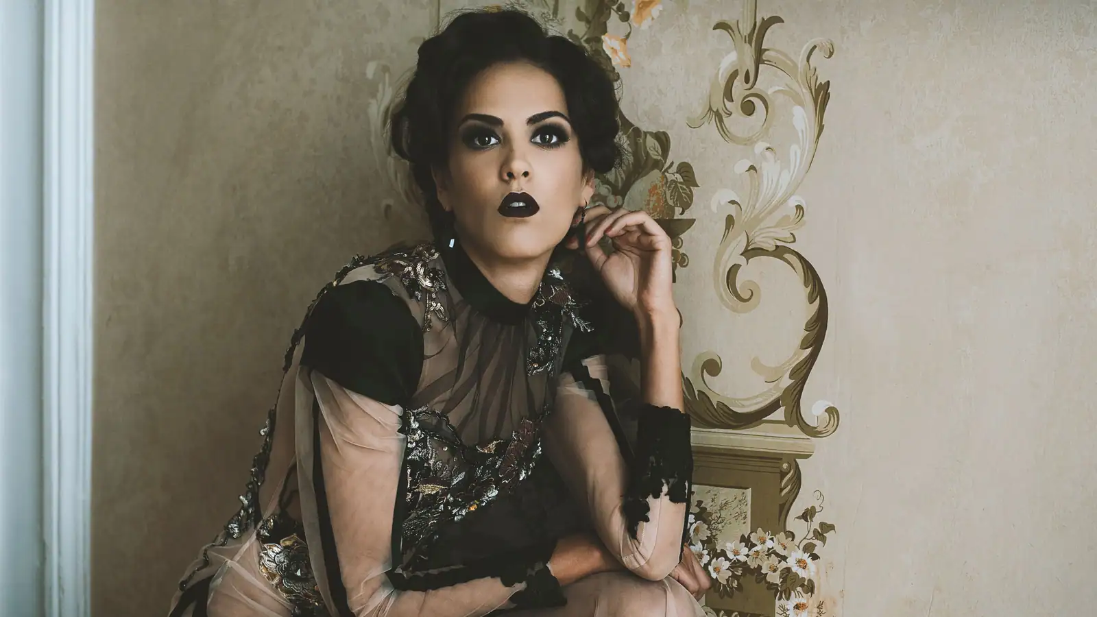 Femme au maquillage gothique romantique : œil noir estompé et bouche noire mate, décor victorien