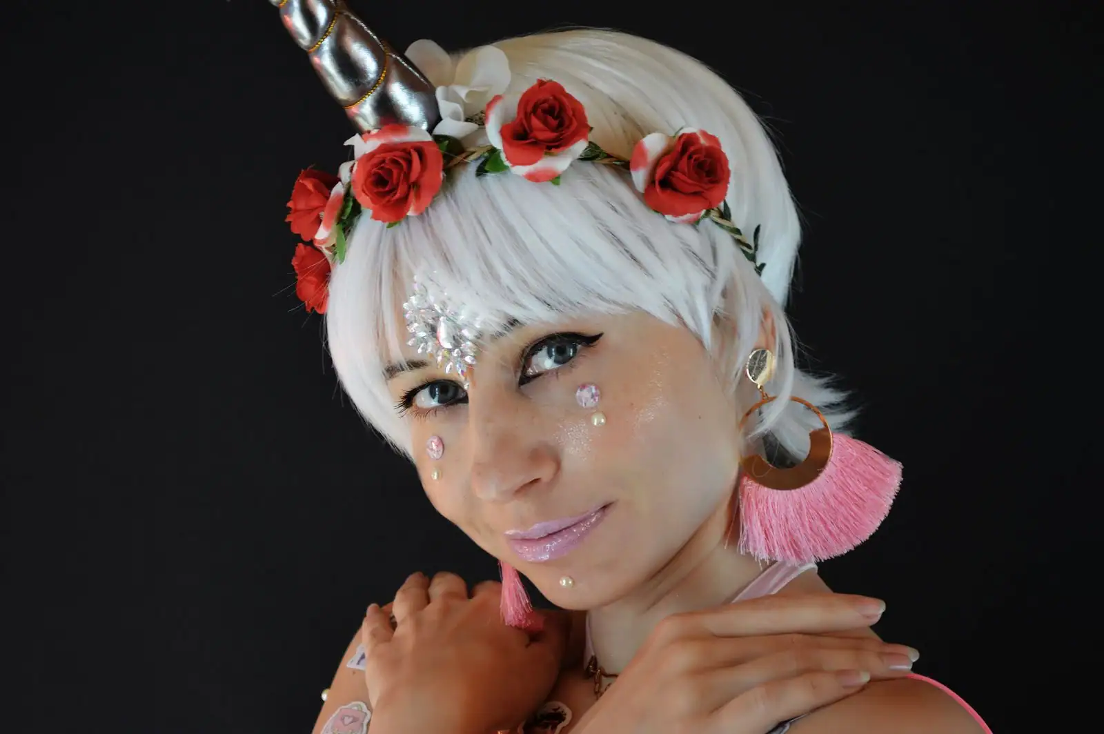 Jeune femme grimée en licorne : corne argentée sur le front, couronne de roses et gemmes sur le visage.