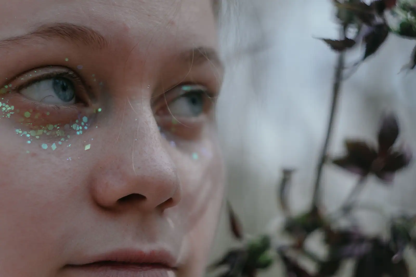 Gros plan sur le visage d’une fillette maquillée de paillettes pastel sous les yeux, style princesse.