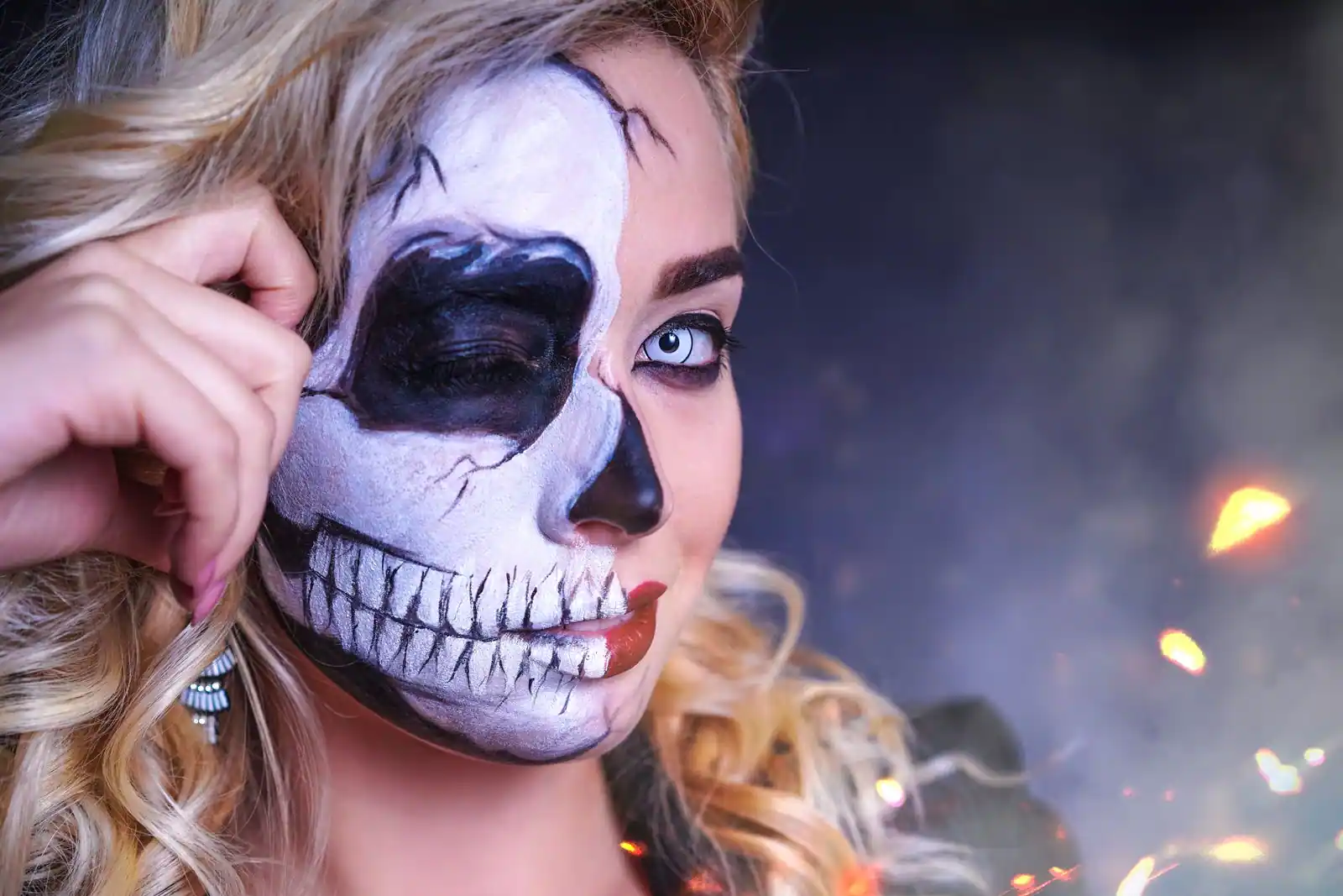 Visage à moitié peint en crâne, l'autre moitié laissée nue, maquillage d'Halloween en gros plan.
