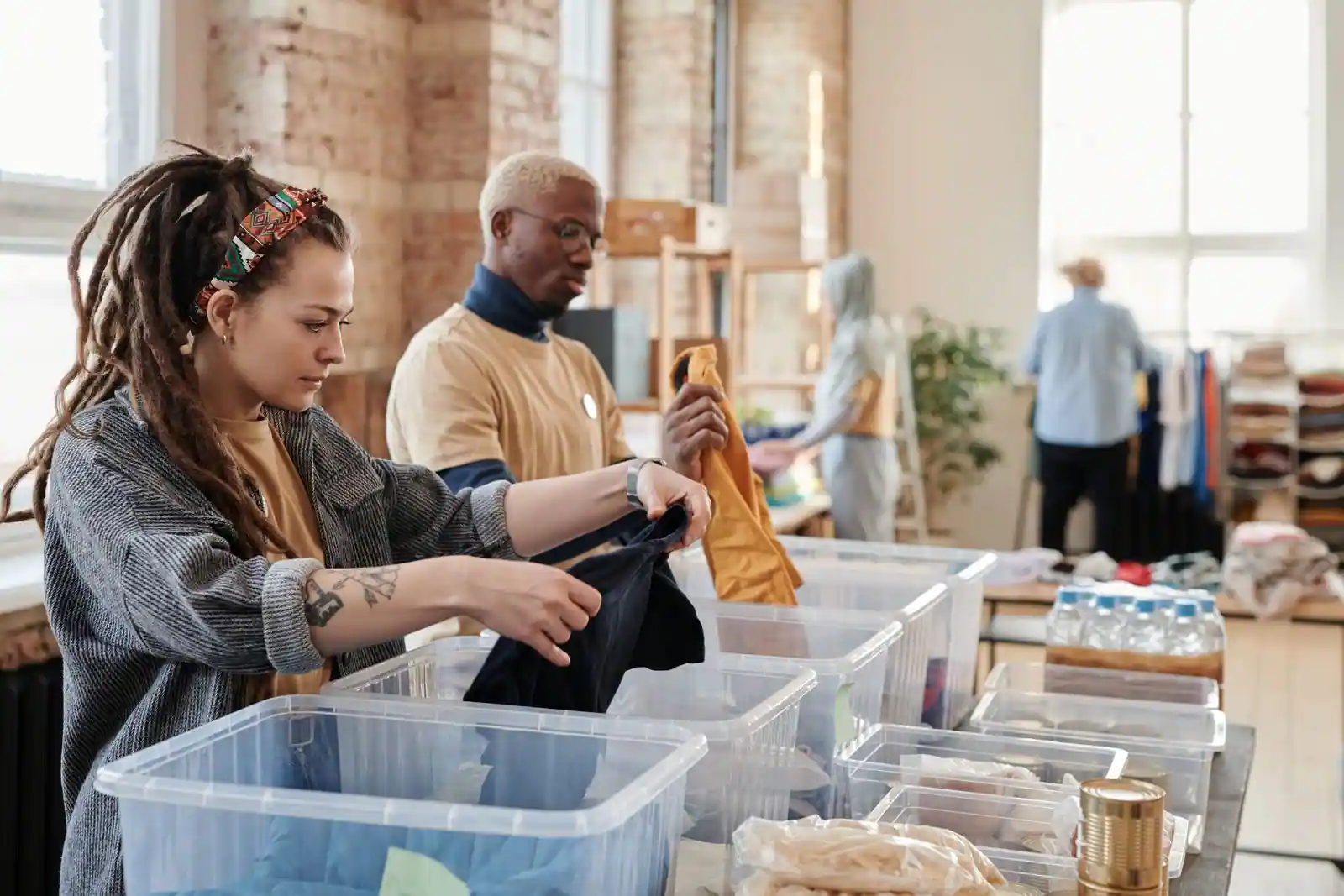 Bénévoles triant des vêtements collectés dans des bacs en plastique, à l'intérieur d'un centre de collecte