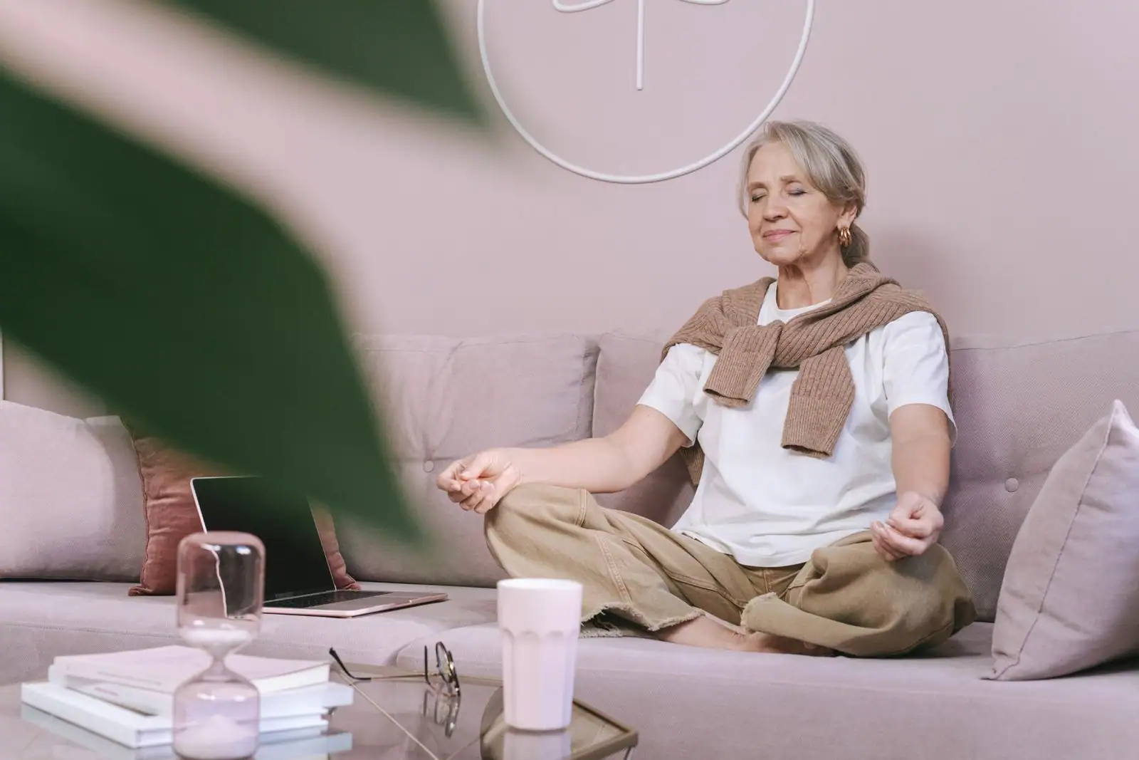Femme assise en tailleur, les yeux fermés, en méditation de pleine conscience dans un salon lumineux