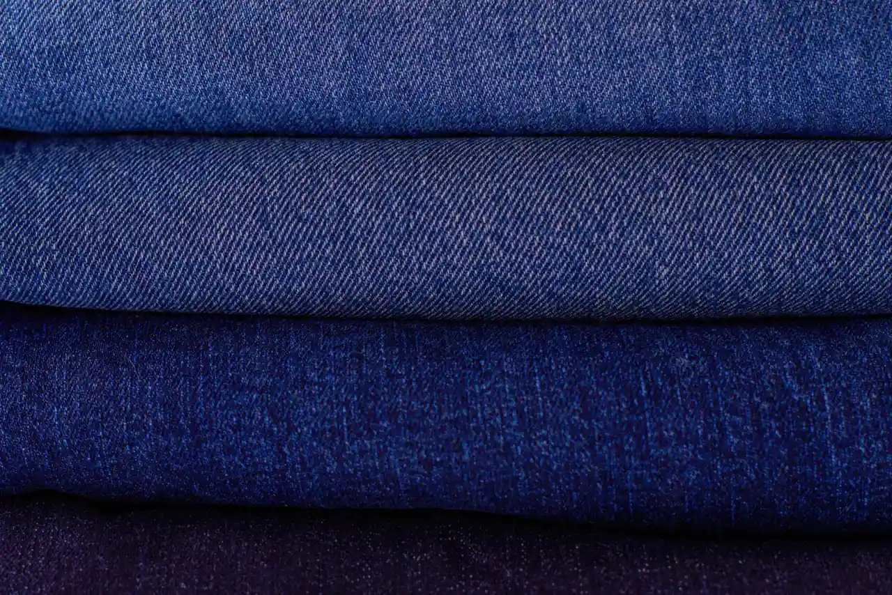 Gros plan sur une pile de jeans en denim bleu, soigneusement pliés et empilés les uns sur les autres.